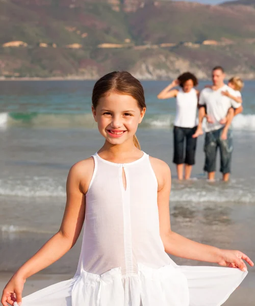 可爱的女孩与她的父母和她的弟弟在背景中的沙滩上 — 图库照片