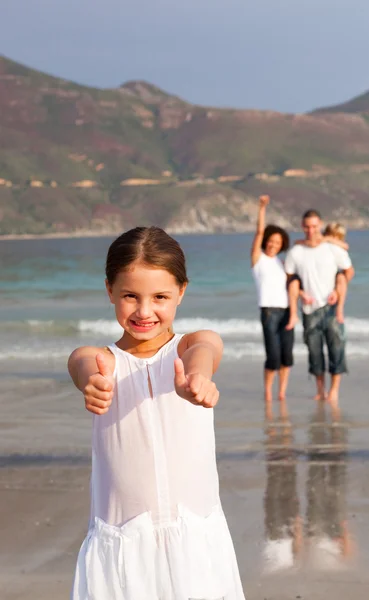 可爱的女孩与她的父母和她的弟弟在背景中的沙滩上 — 图库照片