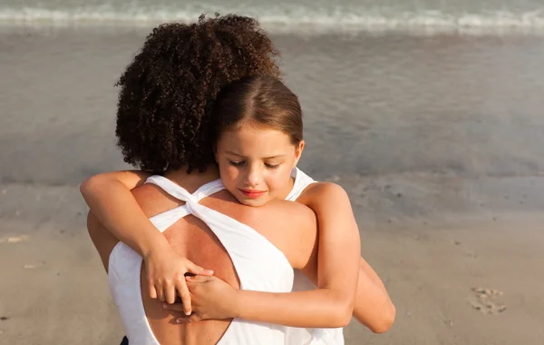Leuk meisje en haar moeder een knuffel gelet op het strand — Stockfoto
