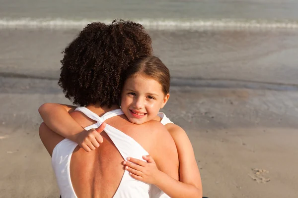 Carino ragazza e sua madre avendo un abbraccio sulla spiaggia — Foto Stock