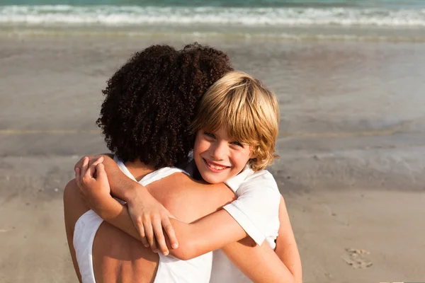 Menino e sua mãe dando um abraço na praia — Fotografia de Stock