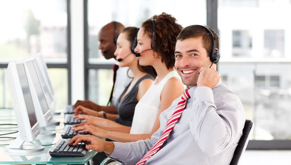 Jungunternehmer, der in einem Callcenter arbeitet, lächelt in die Kamera — Stockfoto