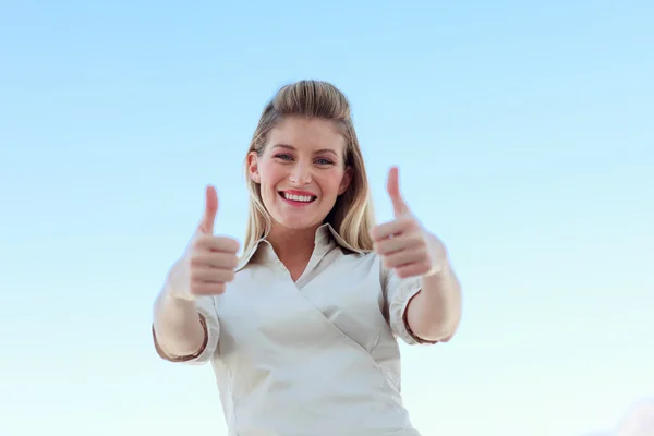 Білявка бізнес-леді посміхається на камеру з великими пальцями вгору — стокове фото