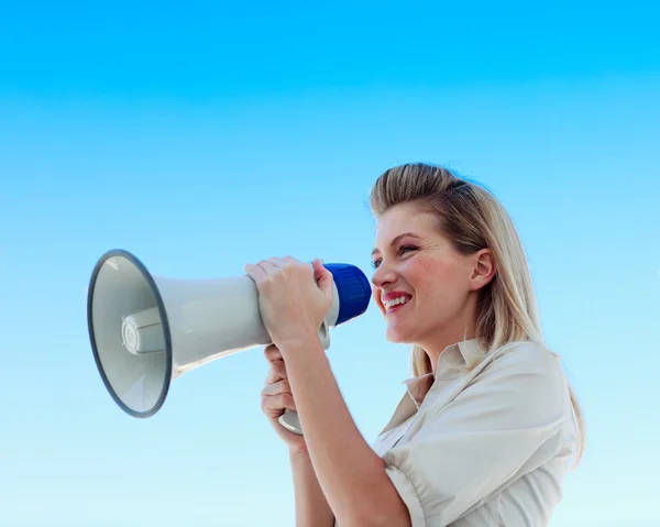 Businesswoman shouting through megaphone against blue sky — Stock Photo, Image