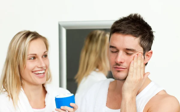 Uomo mettendo crema sul suo viso con sua moglie — Foto Stock