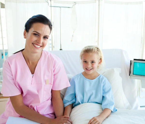 Femme médecin avec sa petite patiente assise sur un lit d'hôpital Image En Vente