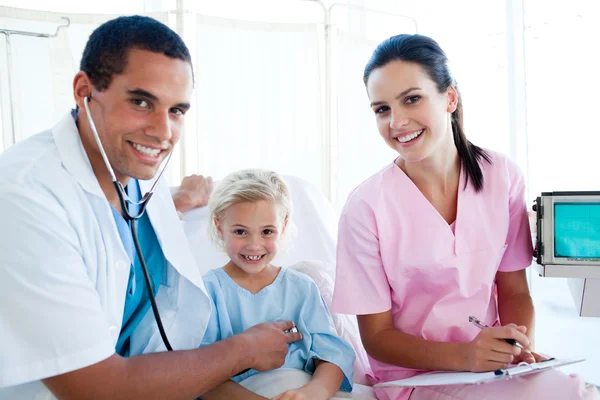 Un dottore controlla il polso di una bambina sorridente Immagine Stock