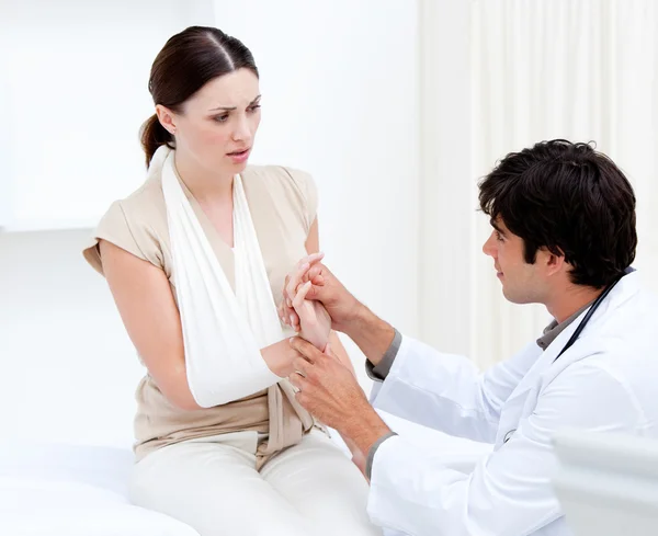 Joven médico masculino examinando a la paciente femenina tomando su brazo Imagen de stock