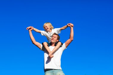 Youth sitting on his father's shoulders clipart