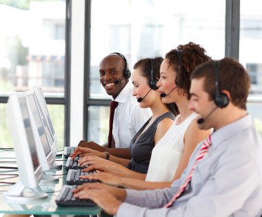 Smiling African-American businessman in a call center clipart