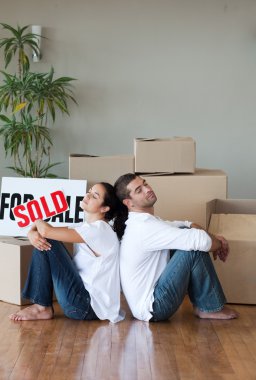 Smiling couple with unpacking boxes moving to a new house clipart