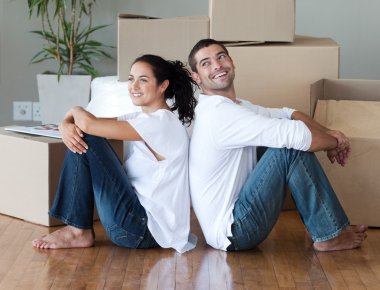 Lovely couple with unpacking boxes moving to a new house clipart