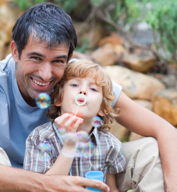 Portrait of a father and son blowing bubbles clipart