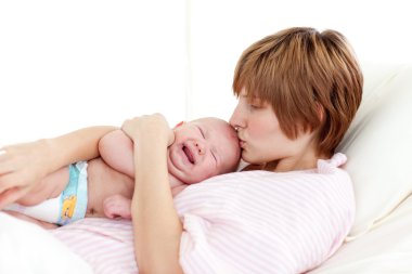 Mother kissing her newborn baby clipart