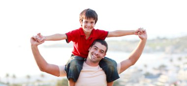 Young man giving child piggyback ride clipart