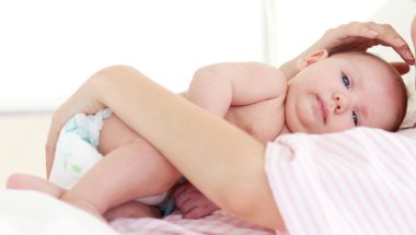 Newborn baby with his mother in bed clipart