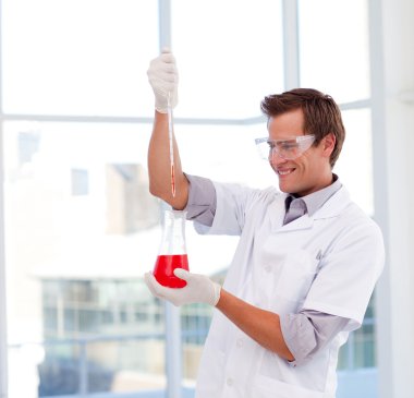 Smiling scientist examinig a test-tube clipart