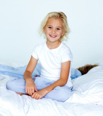 Little girl in bed smiling at the camera while her brother is sl clipart