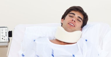 Male patient with a neck brace lying on a bed clipart