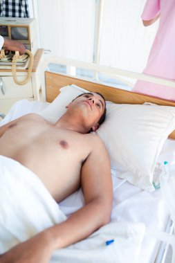 Barechested patient lying on a hospital bed clipart