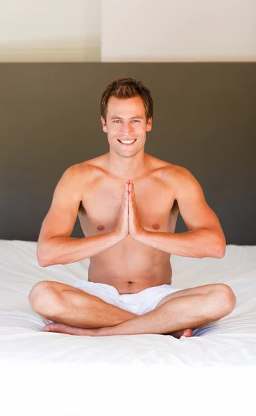 Smiling man meditating on bed — Stock Photo, Image