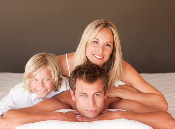 Счастливая пара и сын наслаждаются вместе в постели — стоковое фото
