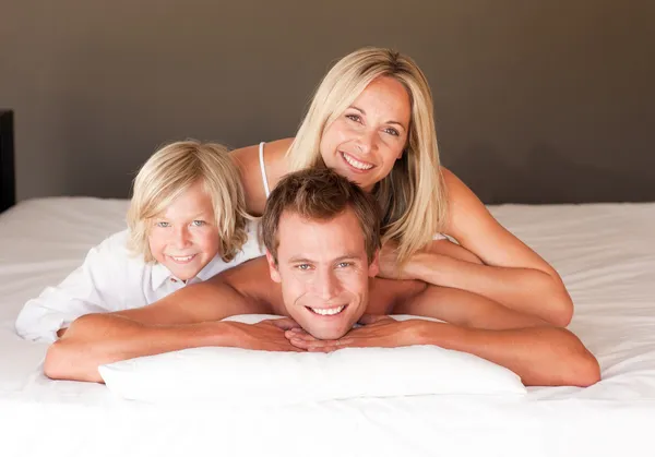 Happy couple and son enjoying together in bed — Stock Photo, Image