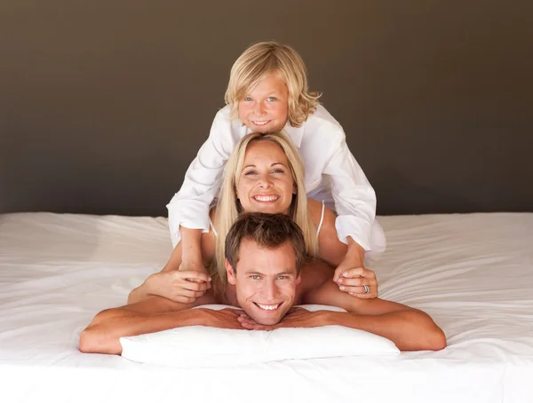 Sevimli küçük bir çocuk ve ailesi eğleniyor yatakta yatıyordu — Stok fotoğraf