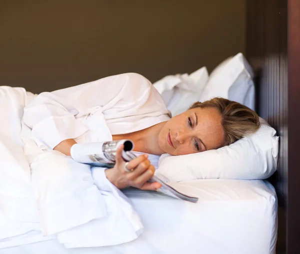 Молодая женщина читает журнал в постели — стоковое фото