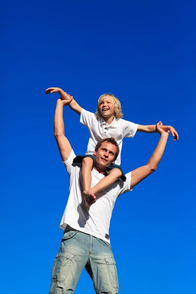 Man ger ung pojke piggyback rida leende — Stockfoto