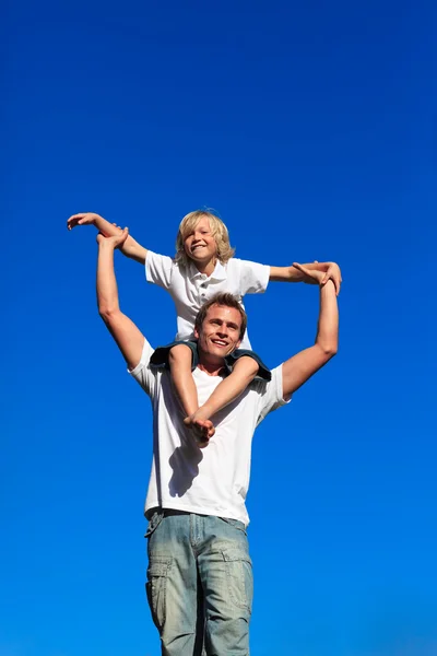 Jongen zit op de schouders van zijn vader. — Stockfoto