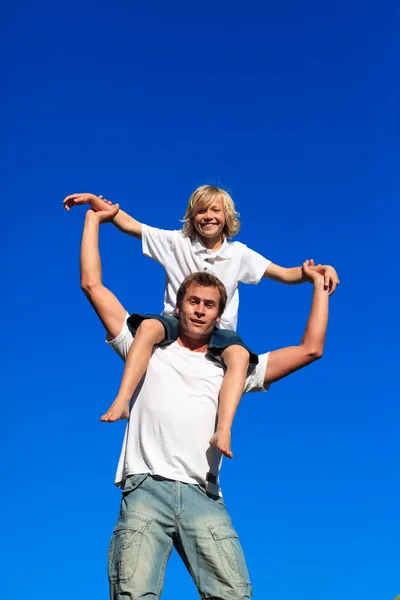 Отец катает своего сына на спине — стоковое фото