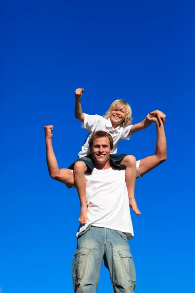 Criança forte sentada nos ombros de seu pai — Fotografia de Stock