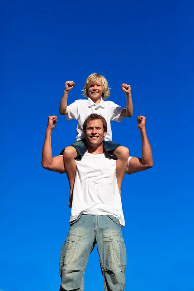 Strong son sitting on his father's shoulders — Stock Photo, Image