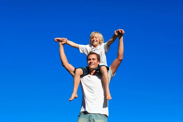 Kid zittend op zijn vaders schouders — Stockfoto