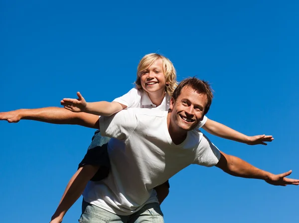 Jovem homem dando jovem menino piggyback passeio — Fotografia de Stock