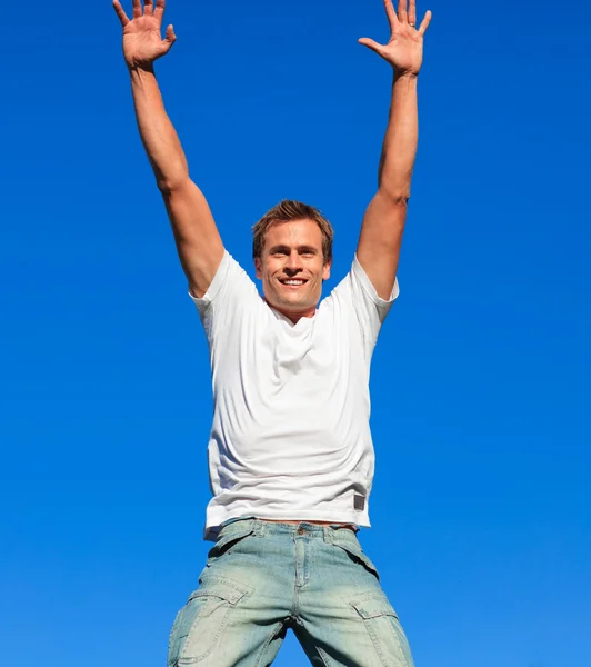 Молодой человек прыгает в воздух против синего неба — стоковое фото