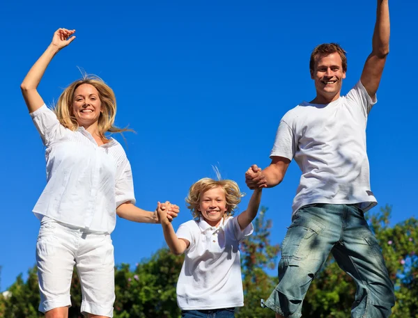 Young family jumping in the air against thr blue sky — Stock Photo, Image