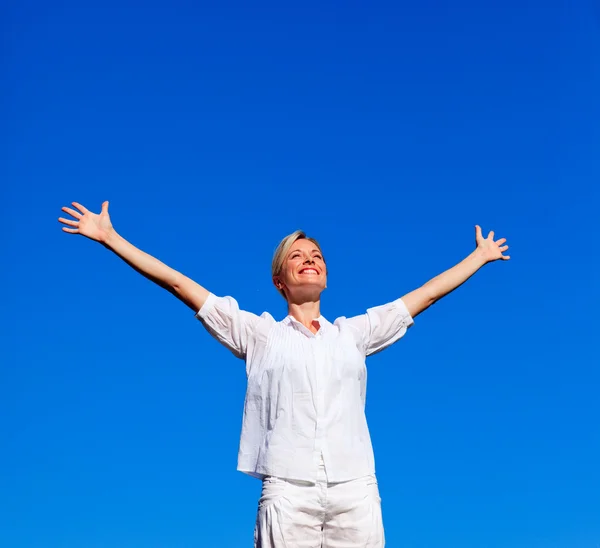 Ung kvinna göra övningar mot blå himmel — Stockfoto