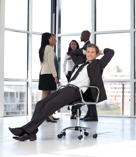 Manager rilassante in ufficio con team in background — Foto Stock