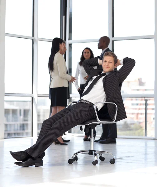 Manager entspannt im Büro mit Team im Hintergrund — Stockfoto