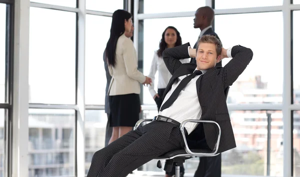Manager rilassante in ufficio con team in background — Foto Stock