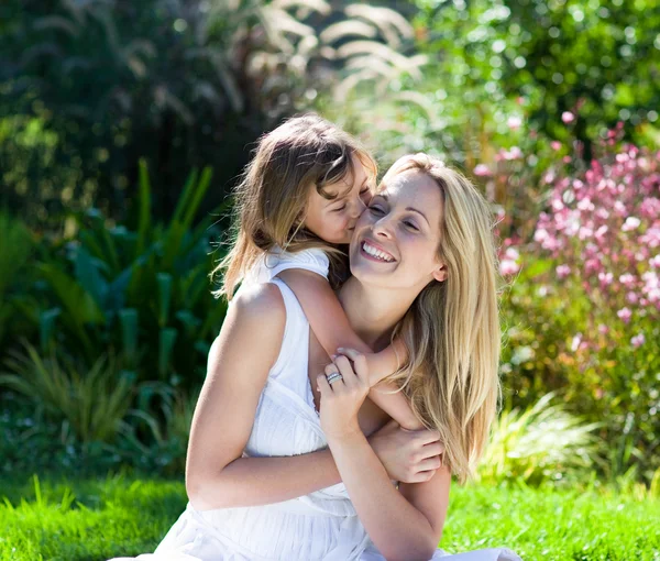 En liten flicka kysser sin mamma — Stockfoto