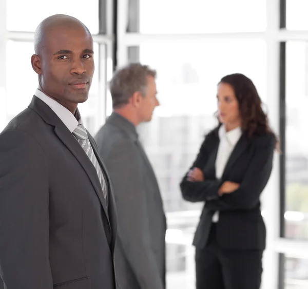 Serious business leader looking at camera in front of team — Stock Photo, Image