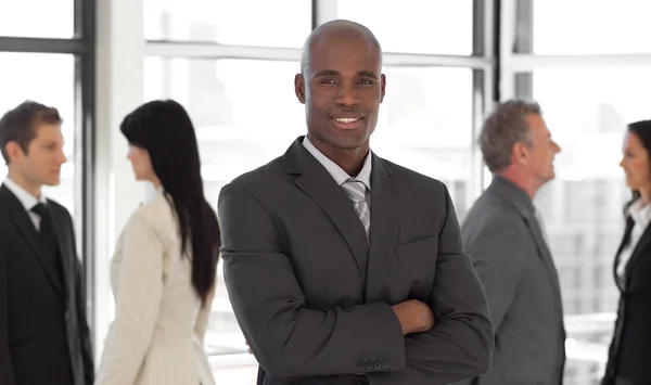 Smiling ethnic business leader in front of team — Stock Photo, Image