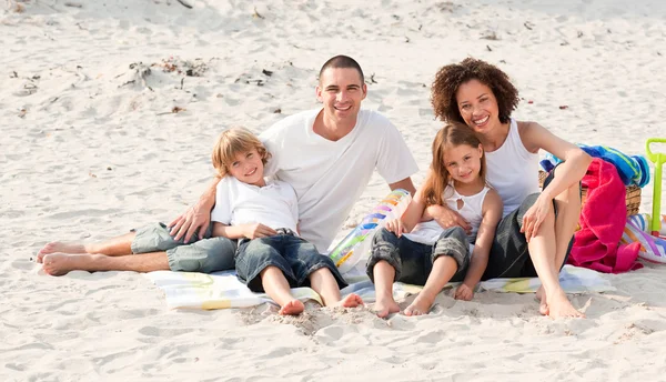 Famiglia che gioca seduta su una spiaggia — Foto Stock