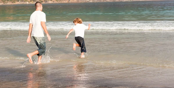 Far och son spelar på en strand — Stockfoto