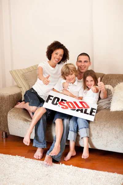 Família feliz sentada em um sofá — Fotografia de Stock
