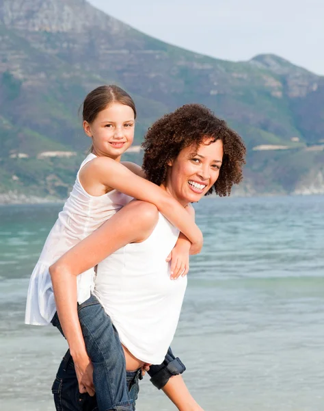 Mãe dando filha piggyback passeio na praia — Fotografia de Stock