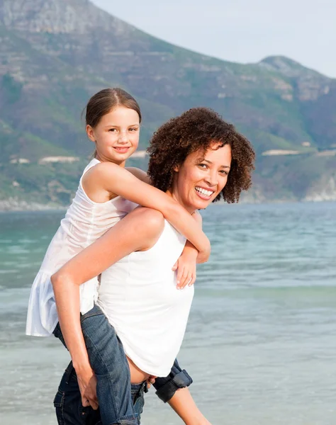 Moeder dochter geven piggyback ritje op het strand — Stockfoto